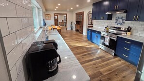 A modern kitchen with a marble countertop, wooden flooring, and blue cabinets. - The Quilting House a charming craftsman home centrally located in Burley (Burley)