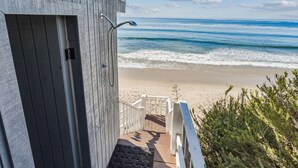 Una terraza de madera con vista a la playa y al océano.