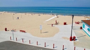 Una spiaggia con una passeggiata in cemento, panchine e una torretta per i bagnini.