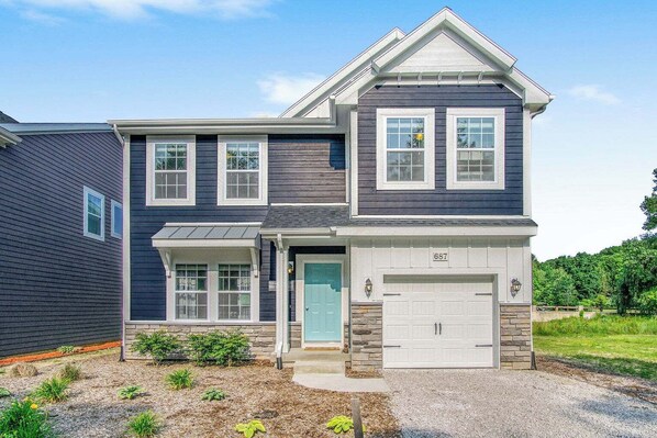 A two-story house with a garage, a front porch, and a stone foundation. - Relax and play at Indigo Haven--spacious home close to beach and pools! (South Haven)