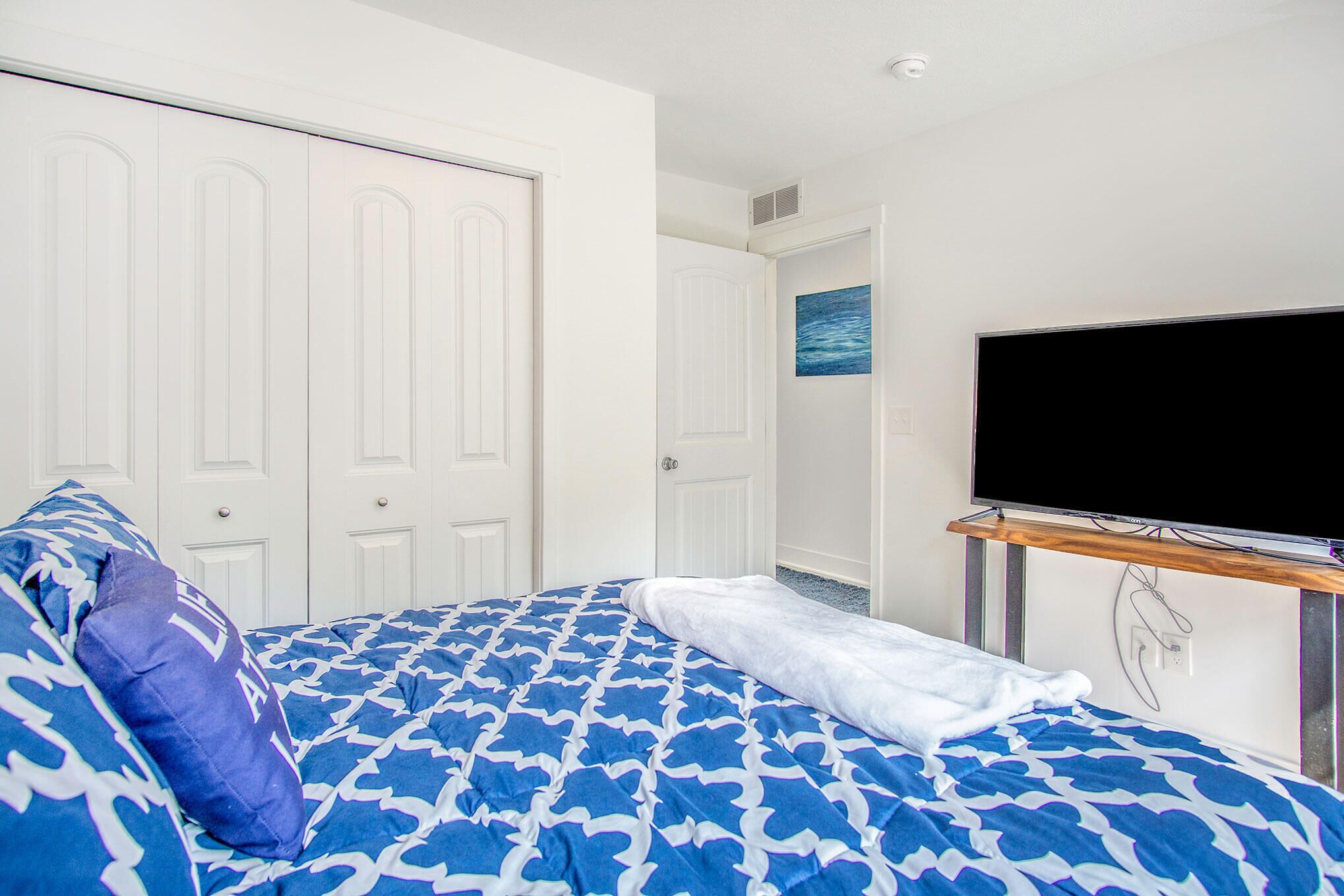 Una camera d'albergo con un letto, una TV su un mobile e una porta che conduce a un'altra stanza.