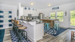 Una cucina moderna con mobili bianchi, un'isola centrale con sgabelli e un cartello con la scritta 'LAKE'.