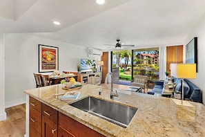 A modern kitchen with a granite countertop, stainless steel sink, and wooden cabinets. - Papakea Villas | Ocean View 2 BR Sleeps 8 | Car Incl. w/ 6+ Nights | PKD ML-3520 by KBM (Lahaina)