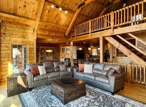 Ein Blockhaushaus-Interieur mit einem großen, L-förmigen Sofa, einem Holztisch und einem gemusterten Teppich.