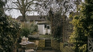 A garden patio with a table and chairs, surrounded by stone walls and plants. - Rasen Stay Cottage - Cosy Vintage  Retreat in Lincoln (Lincoln)