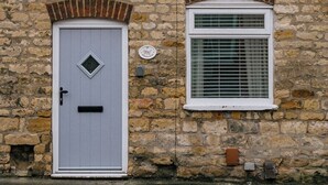 A stone building with a white door, a small window, and a brick chimney. - Rasen Stay Cottage - Cosy Vintage  Retreat in Lincoln (Lincoln)
