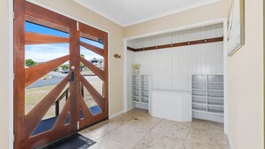 A hallway with a wooden door, white shelving, and a small plant. - Big Red Beach House - Rainbow Beach (Rainbow Beach)