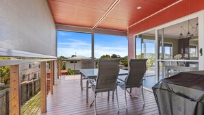 A covered outdoor patio with a table and chairs, a grill, and a view of the surrounding area. - Big Red Beach House - Rainbow Beach (Rainbow Beach)