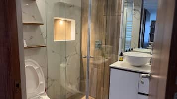 Chuveiro, toalhas de banho, sabonete, papel higiênico