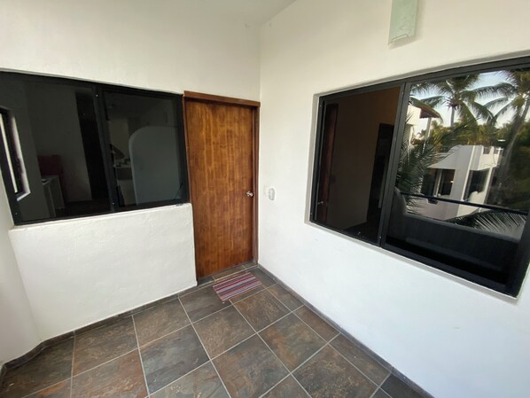 Un pasillo con una puerta de madera y una ventana que ofrece vistas a palmeras.