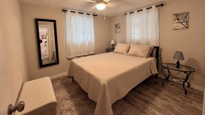 Ein Schlafzimmer mit einem Bett, einem Nachttisch, einer Lampe und einem Deckenventilator.