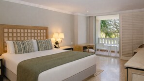 A hotel room with a large bed, a desk, and a balcony with a view of palm trees.