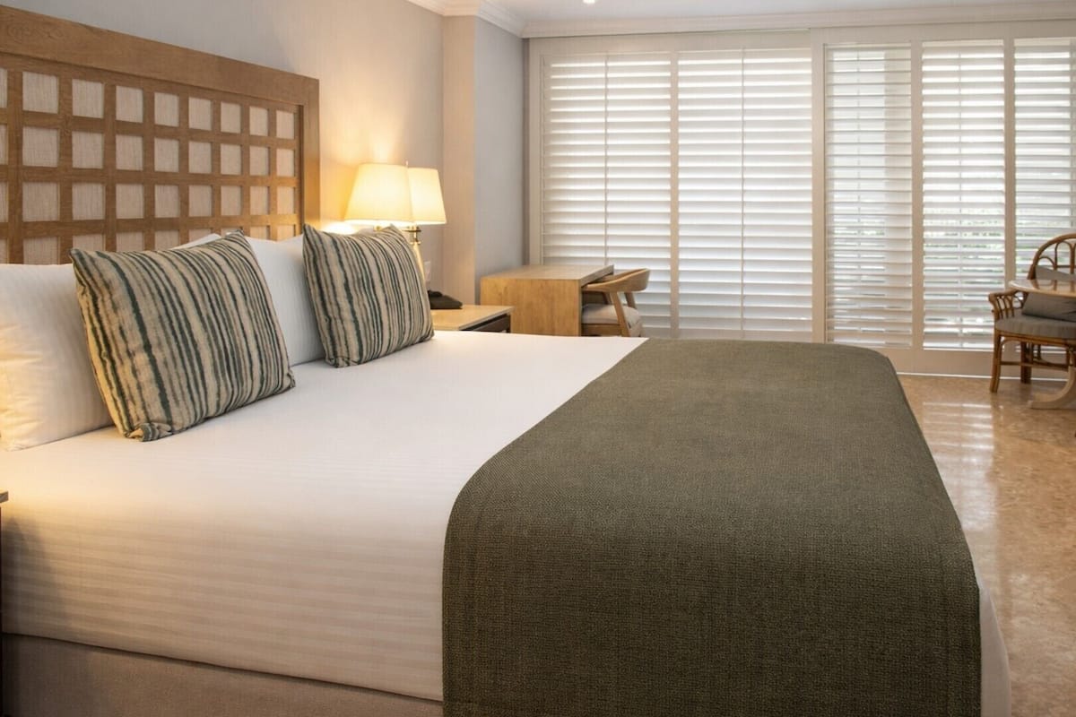 A hotel room with a large bed, a desk, and a chair.