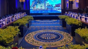 A conference room with a large screen displaying a hotel image, a chandelier, and a patterned carpet. - Princess Mundo Imperial All Inclusive (Acapulco)