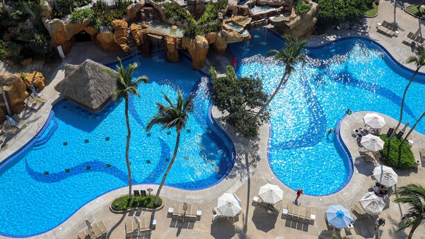 A large, multi-level swimming pool with palm trees and lounge chairs. - Princess Mundo Imperial All Inclusive (Acapulco)