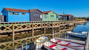 Una hilera de edificios de madera coloridos con un muelle de madera que se adentra en aguas tranquilas, donde hay barcos amarrados.