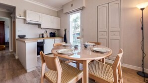 Una cocina compacta con comedor, un refrigerador pequeño y una ventana.