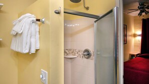 A bathroom with a glass shower enclosure, a towel rack with white towels, a toilet paper holder, and a showerhead. - Sparrow's Nest (Yosemite National Park)