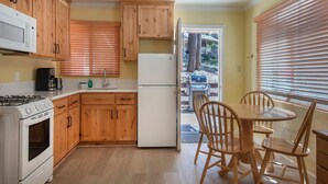 A kitchen with wooden cabinets, a white refrigerator, a stove, and a dining table with chairs. - Sparrow's Nest (Yosemite National Park)