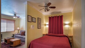 A bedroom with a bed, a ceiling fan, a red curtain, and a small table with a lamp. - Sparrow's Nest (Yosemite National Park)