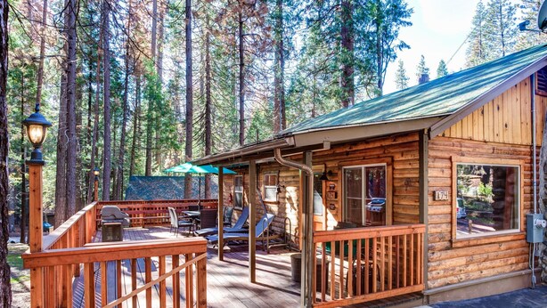 Una baita in legno con veranda, sedute all'aperto e un'ampia finestra.