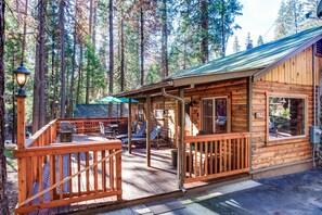 Una cabaña de madera con un porche, mobiliario exterior y un ventanal grande.