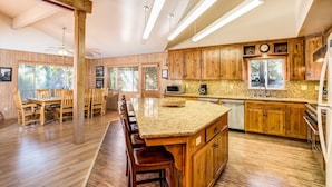A spacious kitchen with wooden cabinets, a large island with bar stools, and modern lighting fixtures. - River Lodge (Yosemite National Park)
