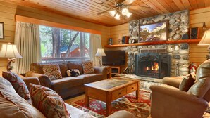 A cozy living room with a stone fireplace, leather sofas, and a television.
