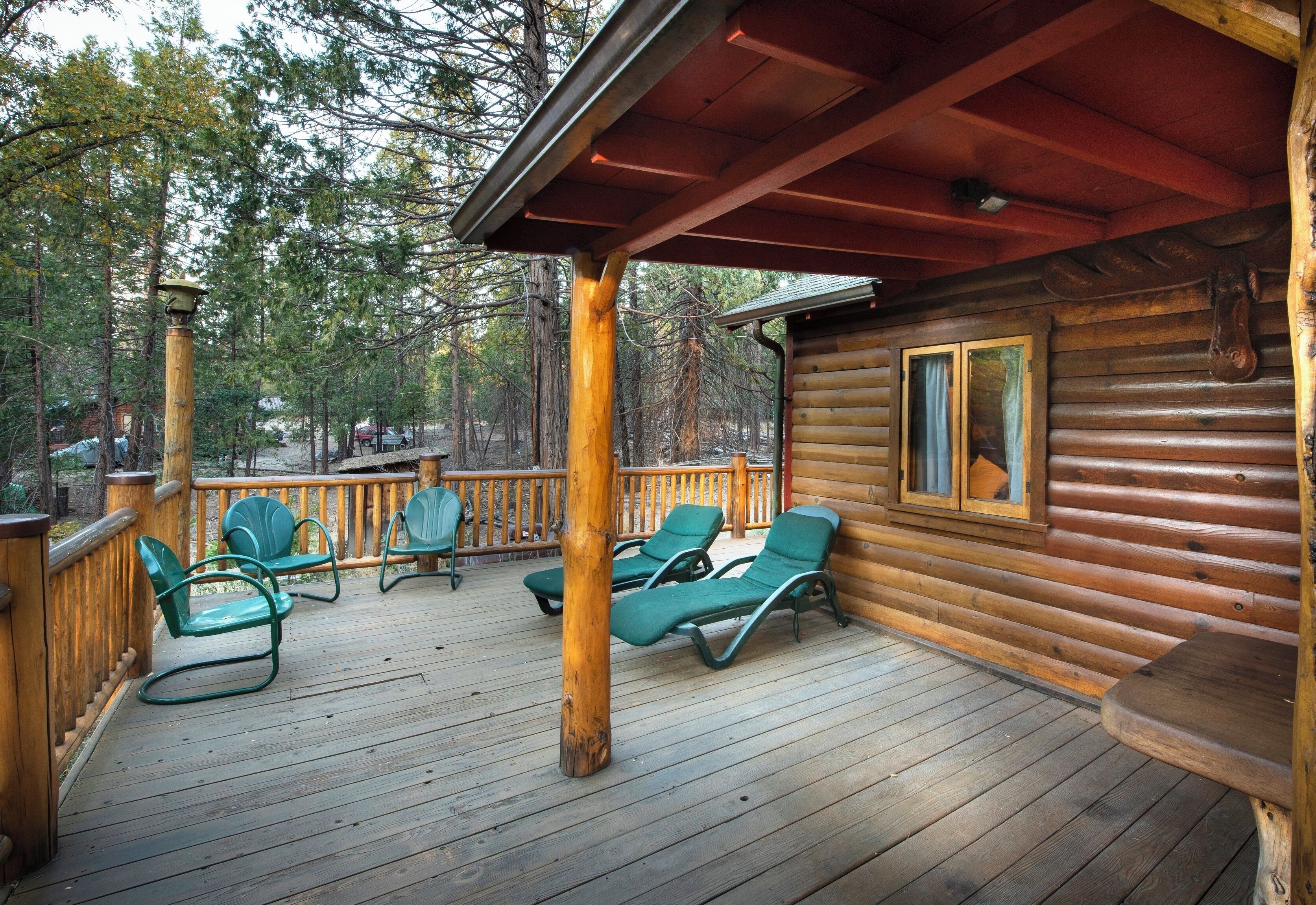A wooden deck with green lounge chairs and a covered area with a red roof.