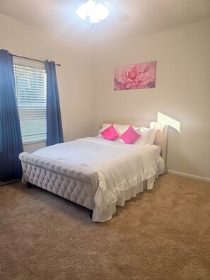 Quarto com cama, ventilador de teto, janela com cortinas e luminária na parede.