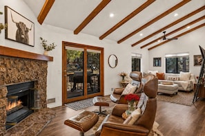 A spacious living room with a fireplace, leather furniture, and a high ceiling with exposed beams. - NEW| Rustic Mountain Home | AC | 10 min to DT Flag (Flagstaff)