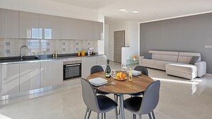 Une cuisine moderne avec un coin repas, comprenant une table et des chaises en bois, un canapé et un îlot de cuisine doté d’un évier et d’appareils électroménagers.