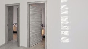 Un couloir avec un mur recouvert de miroirs et une porte donnant sur une chambre à coucher.