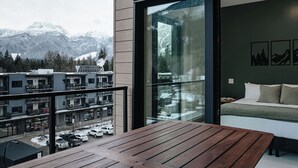 Une chambre d’hôtel moderne dotée d’une grande fenêtre donnant sur une montagne enneigée et un parking.
