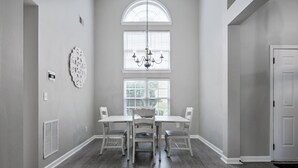 A dining area with a large table and four chairs, a chandelier, and a window with blinds. - 11 Cobblestone, Cartersville (Cartersville)