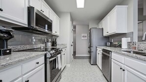 A modern kitchen with white cabinetry, stainless steel appliances, and a patterned floor. - 11 Cobblestone, Cartersville (Cartersville)