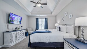 A bedroom with a bed, a desk, a chair, a ceiling fan, a TV, and a window with curtains. - 11 Cobblestone, Cartersville (Cartersville)