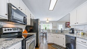A kitchen with white cabinets, a microwave, stove, and dishwasher. There is a window with a view of greenery outside. - 13 Windfield Dr, Cartersville (Cartersville)