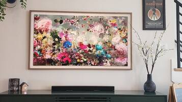 A framed floral artwork on a wall above a dark green dresser with drawers.