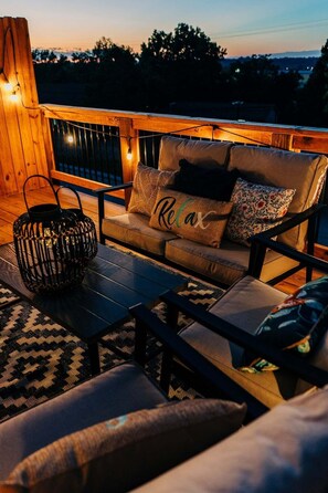 A cozy outdoor seating area with a sofa, a coffee table, and a woven basket. - 41 W High St (Clarksville)