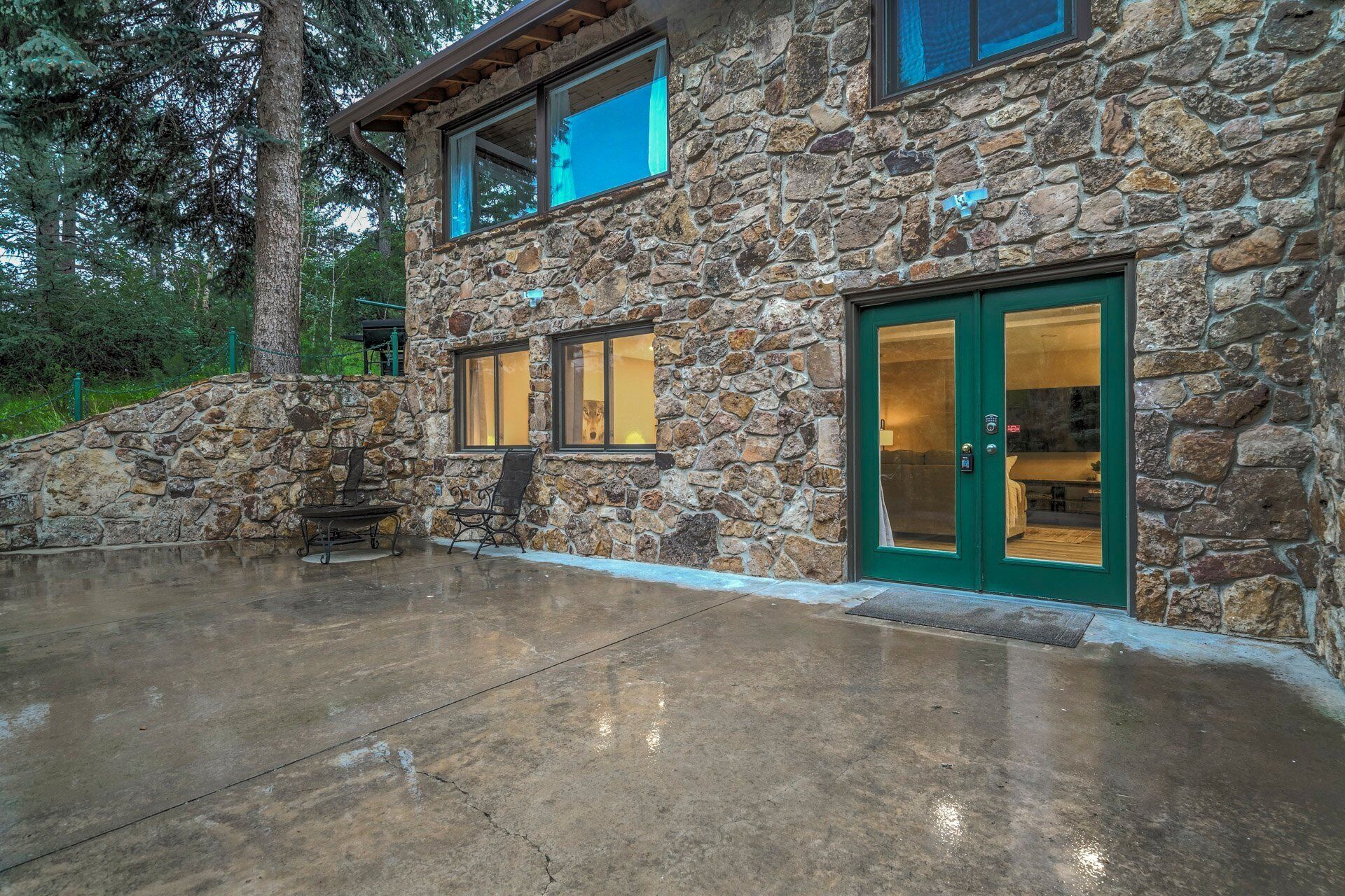 Un edificio de piedra con un patio, ventanas grandes y una puerta verde.