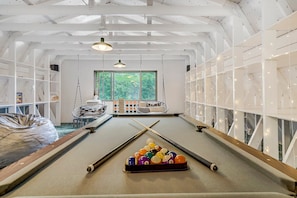 A pool table with billiard balls, a hanging light fixture, and a window with a view of greenery. - 4925 Pike Unit2 (Cascade)