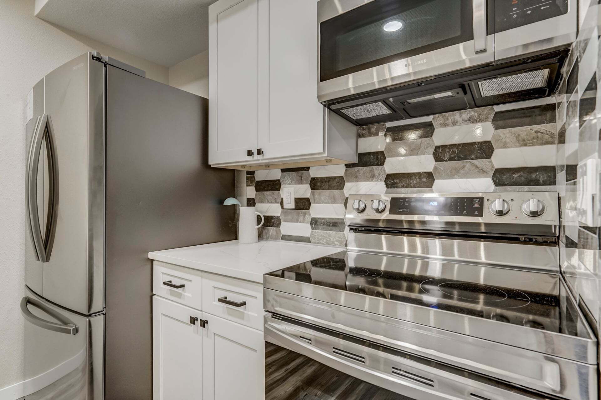 A modern kitchen with stainless steel appliances, a microwave, and a checkered backsplash.