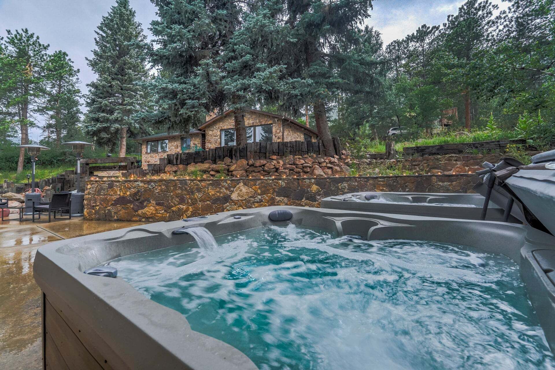 A spa area with hot tubs and a stone house surrounded by trees.