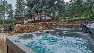 A spa area with hot tubs and a stone house surrounded by trees.
