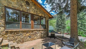A stone building with large windows, outdoor seating, and a grill area. - 4925 Pike (Cascade)