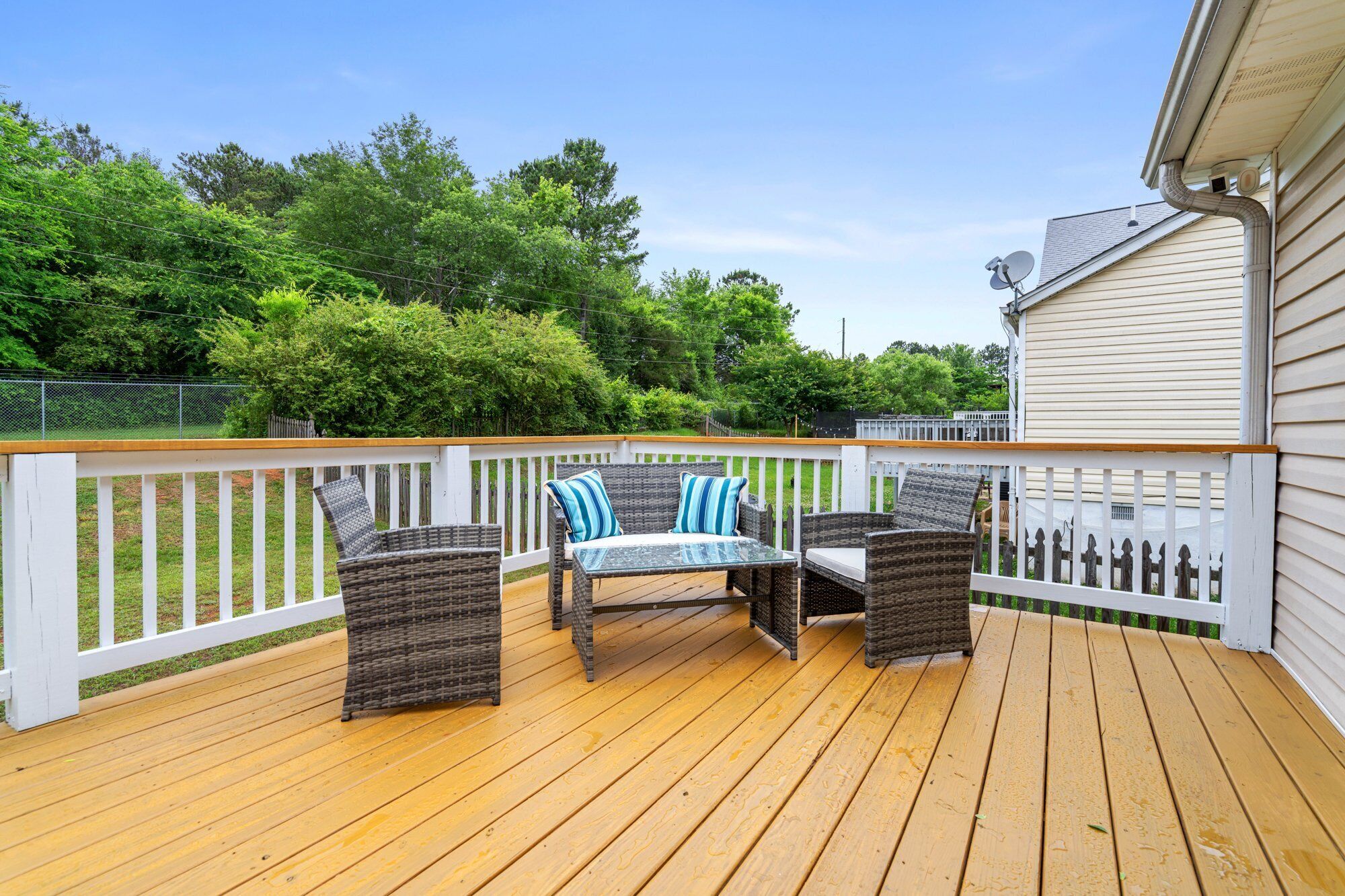 A wooden deck with wicker furniture and a white railing.