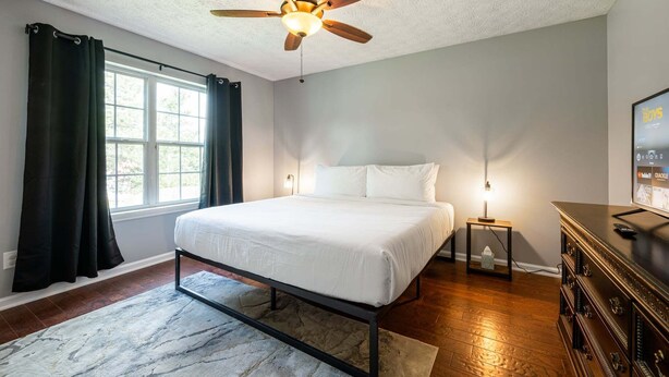 A bedroom with a bed, a ceiling fan, a window with curtains, a nightstand, and a dresser. - 18 Larkspur Ln Emerson (Emerson)