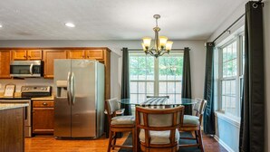 A kitchen with wooden cabinets, a stainless steel refrigerator, a microwave, and a dining table with chairs. - 18 Larkspur Ln Emerson (Emerson)