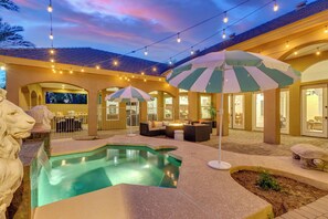 A pool area with a fountain, outdoor seating, and string lights. - Cloud Chandler (Chandler)